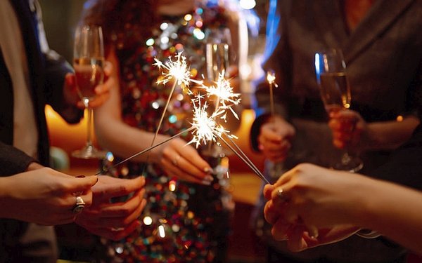Gäste mit Sektgläsern und Wunderkerzen an Silvester